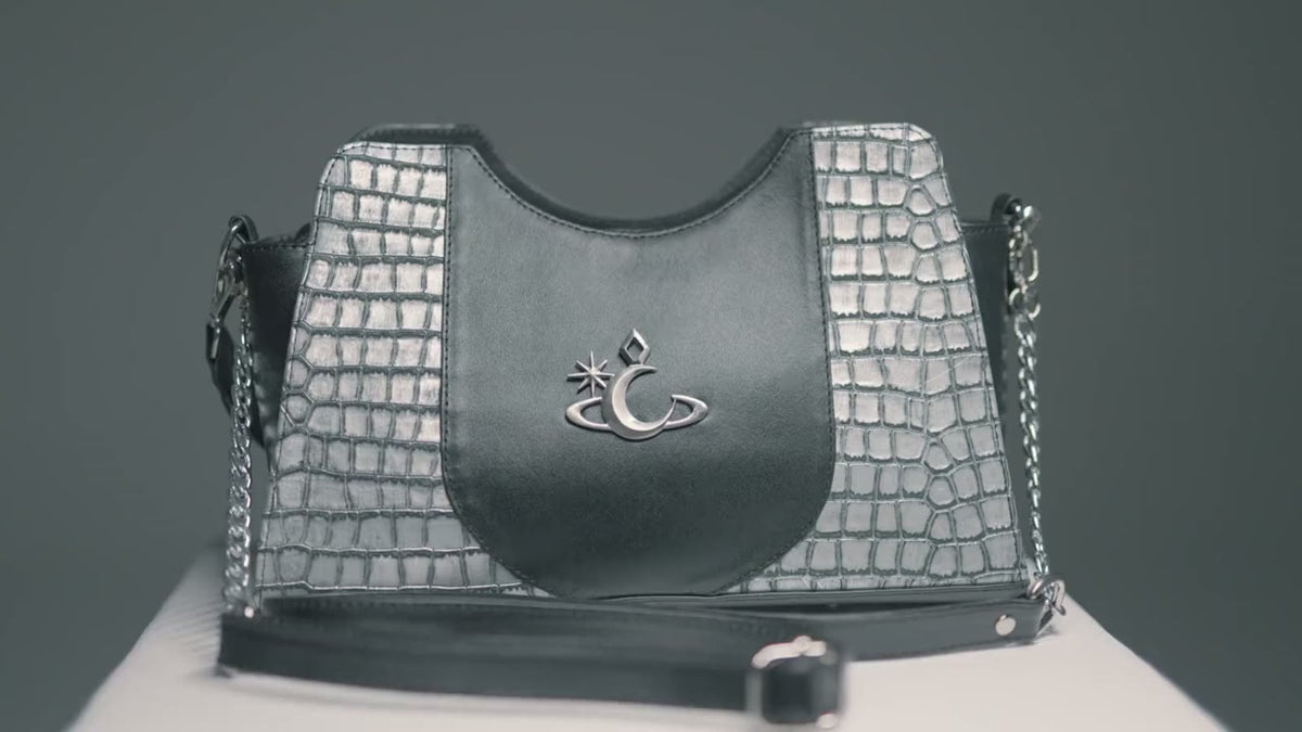 Bolso de croco plata con herraje de luna de Luna Vesper, sobre fondo oscuro