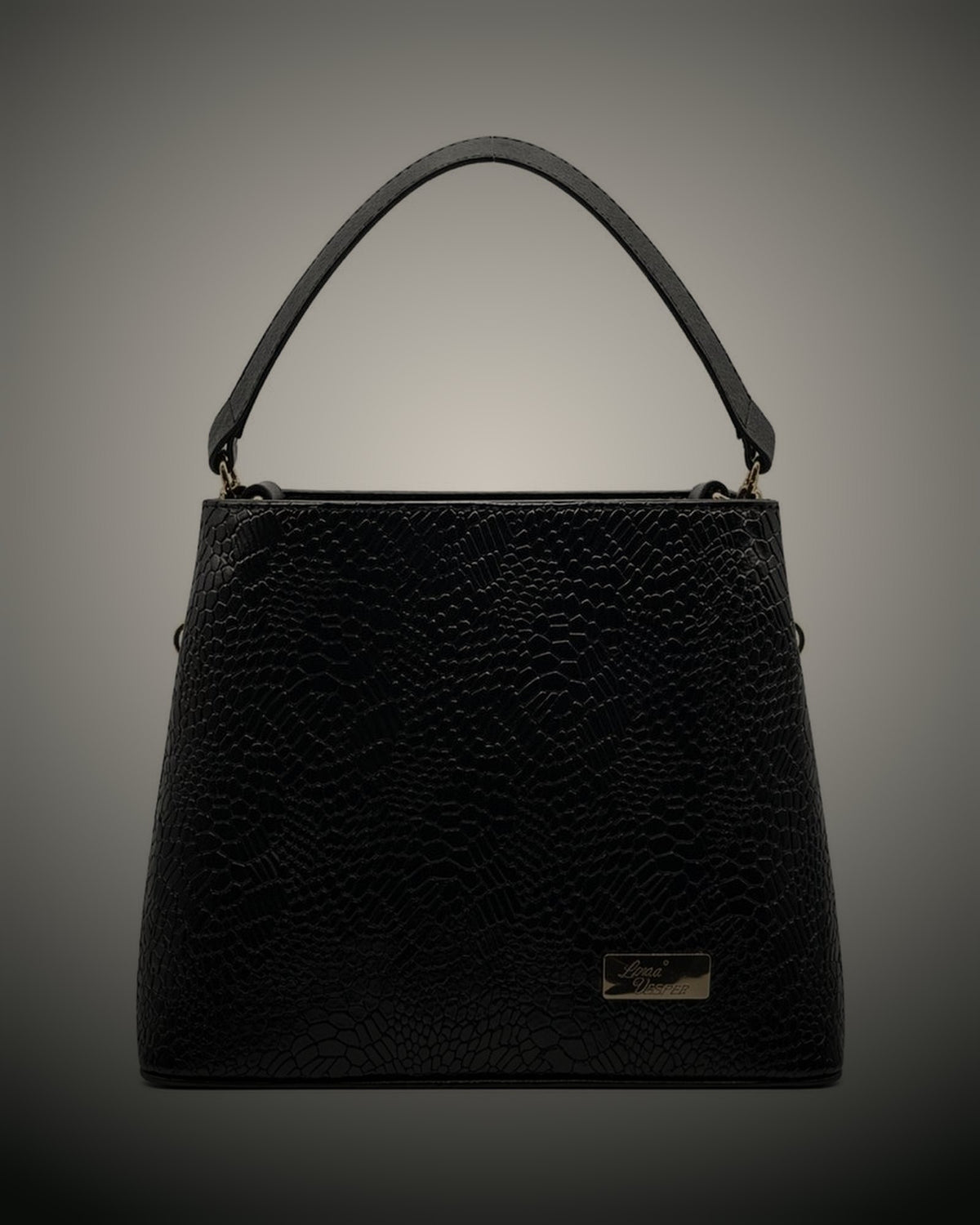 Bolso Amaranta de Luna Vesper: cuero negro grabado, asa superior y la placa de la casa, sobre un fondo de estudio en penumbra.
